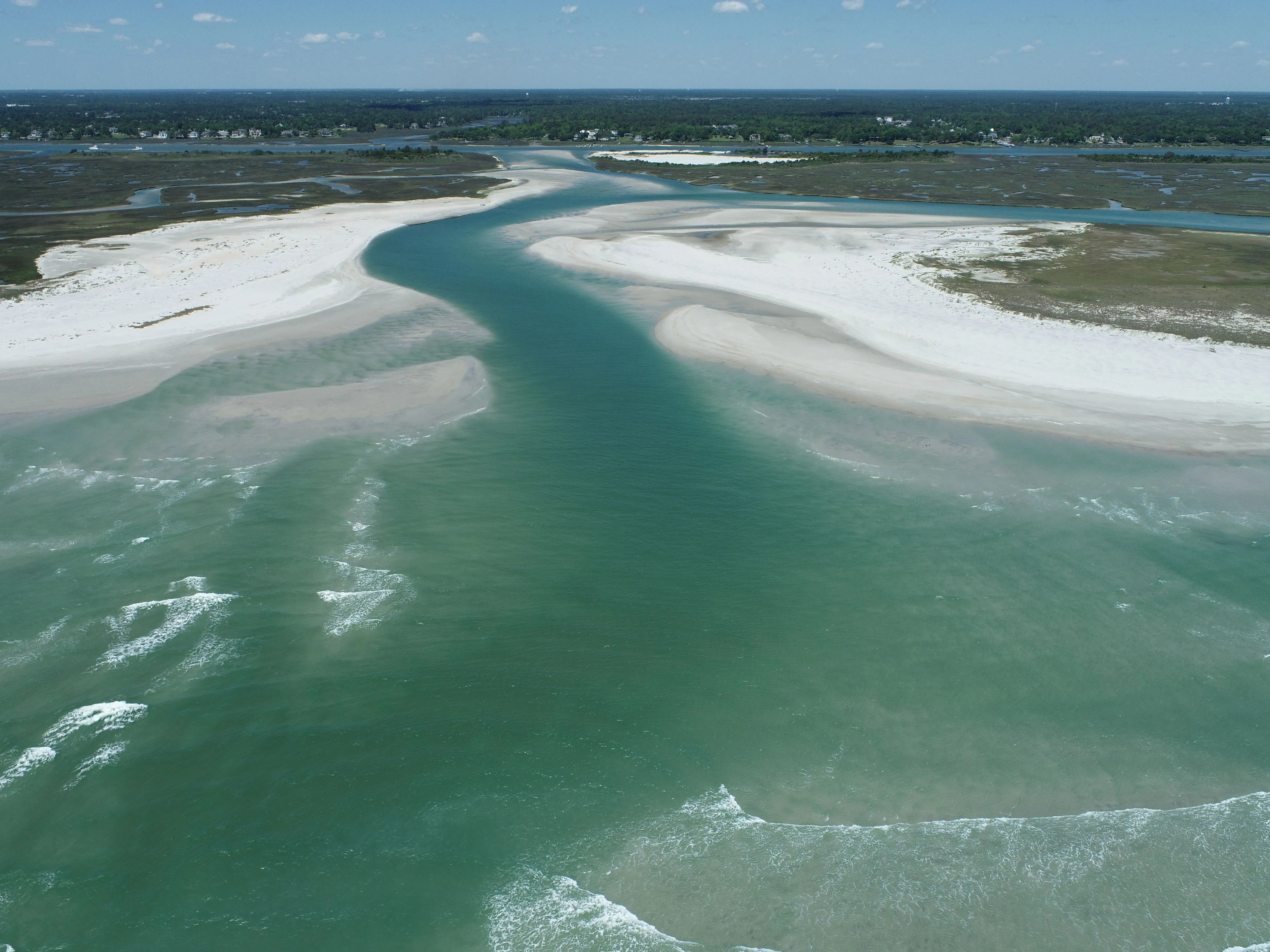 An aerial view of a tidal inlet, beaches, and coastal wetlands