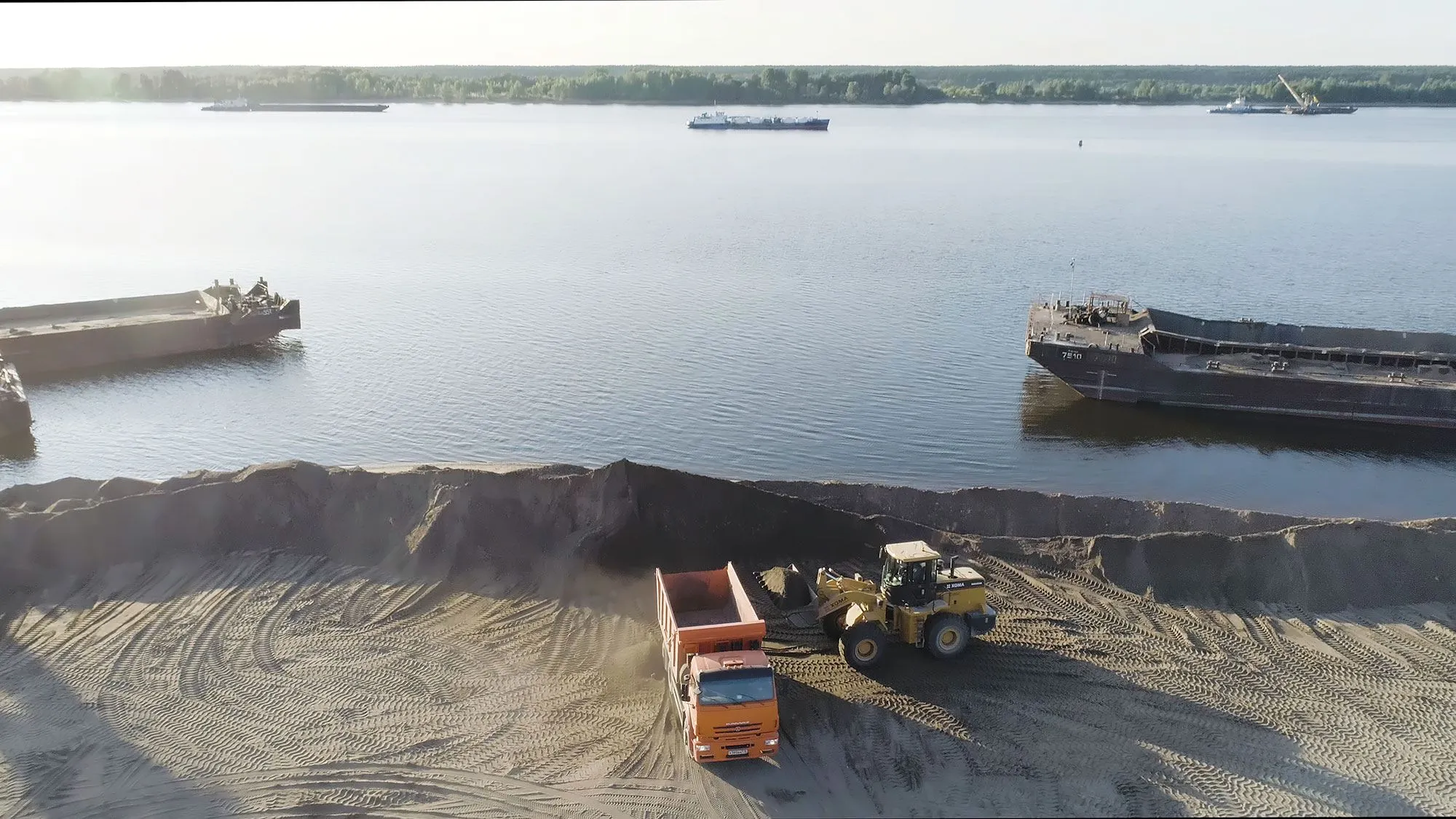 Heavy equipment moving dredged material beside a waterway