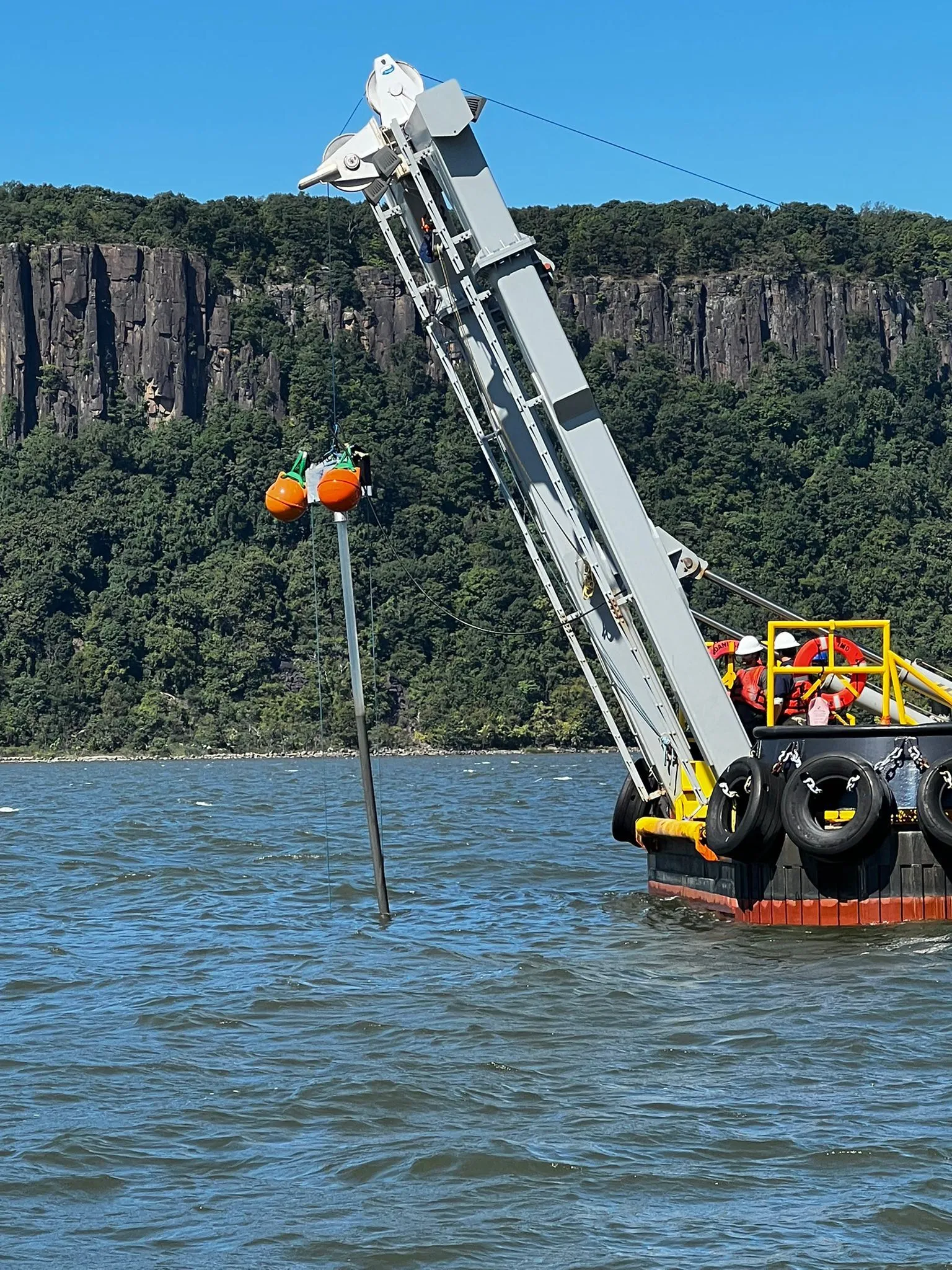 A research vessel lowering geotechnical sampling equipment into the water